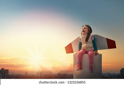 Little child playing pilot. Girl on the background of sunset sky. Kid in an astronaut costume dreaming of becoming a spaceman. - Shutterstock ID 1323236855