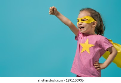 Little child playing superhero. Kid on the background of bright blue wall. Girl power concept. Yellow, pink and  turquoise colors. - Shutterstock ID 1291180936