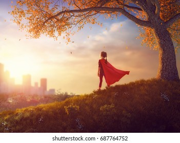 Little child is playing superhero. Kid on the background of autumn landscape. Girl power concept. - Powered by Shutterstock