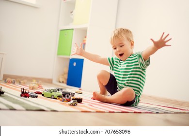 Little child playing with toy cars. Boy sitting on the floor at home
