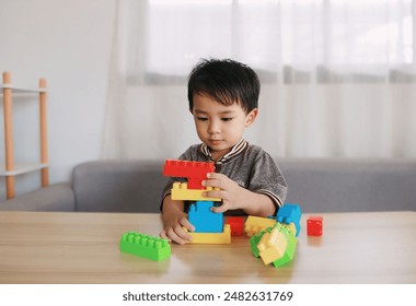 Little child plays with colorful toy blocks. Educational and imaginative toys and games for young children.