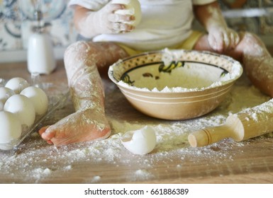 Little child prepare pie on very messy kitchen, covered in white baking flour