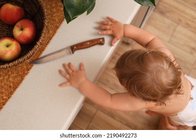 Little Child Reaching For Knife On Light Countertop, Above View. Dangers In Kitchen