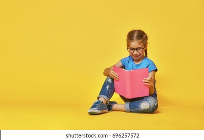 Little Child Is Reading A Book. Kid On The Background Of Bright Color Wall. Education And Success Concept. Yellow, Red And  Blue.