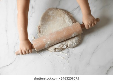 Little child rolling raw dough at white table, top view - Powered by Shutterstock