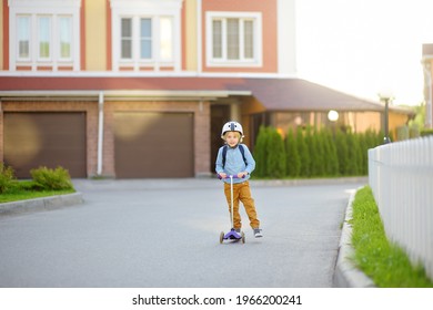 Little Child In Safety Helmet Riding Scooter To School. Preschooler Boy Waving Hand Saying Hi. Safety Kids By Way To School. Back To School And Education For Children Concept.