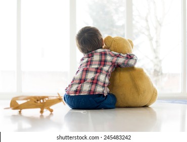 Little child sitting in living room with teddy bear - Powered by Shutterstock