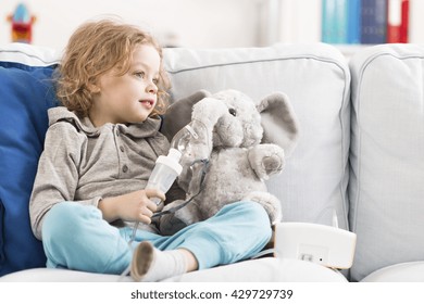 Little Child Sitting On A Sofa With An Elephant Toy With Oxygen Mask