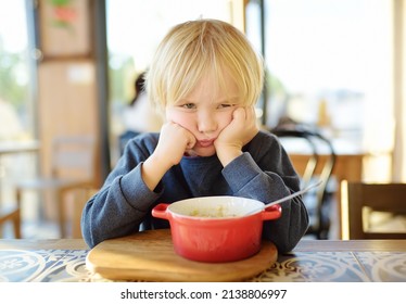 Little Child Sitting The Table In Cafe Or Restaurant And Doesn't Want To Eat. Healthy Food. Kids Diet. Poor Appetite. Grandmother Upbringing.