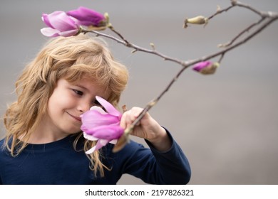 Little Child Is Smelling Flowers On Green Backyard. Adorable Kid On A Summer Meadow And Smelling Flowers. Summer Fun For Family With Kids Outdoors In A Beautiful Spring Garden.