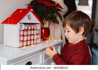 Little child taking chocolate opening first day in handmade advent calendar made from toilet paper rolls. Sustainable Christmas, upcycling, zero waste, kids seasonal activities 