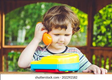 Little Child Talking On A Toy Phone.