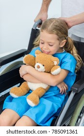 Little Child With Teddy Bear Sitting In Wheelchair In Hospital