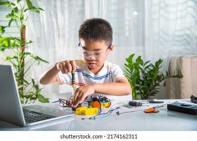 Little Child Tighten The Nut With A Screwdriver To Assemble Car Toy, Asian Kid Boy Assembling The Arduino Robot Car Homework Project At Home, Education AI Technology Workshop School Learning Lesson