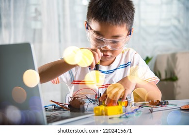 Little Child Tighten The Nut With A Screwdriver To Assemble Car Toy, Asian Kid Boy Assembling The Arduino Robot Car Homework Project At Home, Education AI Technology Workshop School Learning Lesson