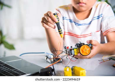 Little Child Tighten The Nut With A Screwdriver To Assemble Car Toy, Asian Kid Boy Assembling The Arduino Robot Car Homework Project At Home, Education AI Technology Workshop School Learning Lesson