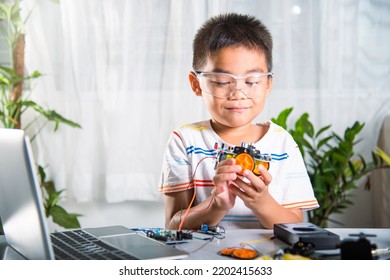 Little Child Trying Assemble Build Wheel To Car Toy, Asian Kid Boy Assembling Wheel Into Arduino Robot Car Homework, Creating Electronic AI Technology Workshop Online School Lesson