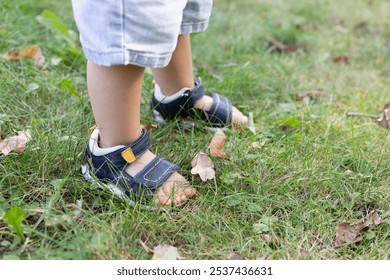 Little child walks in the park in too small sandals. - Powered by Shutterstock