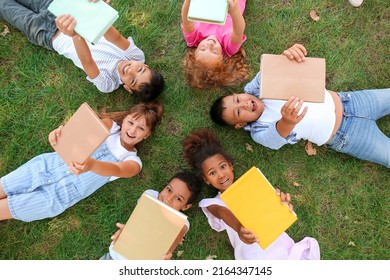 Little children with books lying on green grass in park - Powered by Shutterstock