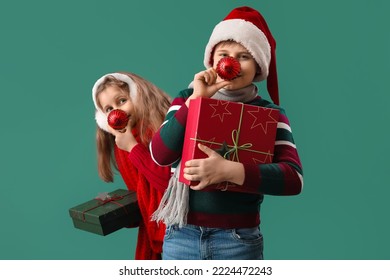 Little children with Christmas balls and presents on green background