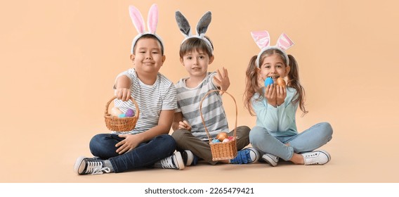 Little children with Easter eggs and bunny ears on beige background - Powered by Shutterstock