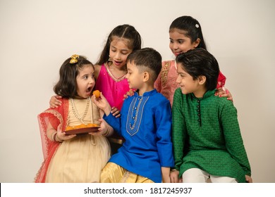 Little Children In Ethnic Wear Enjoying Eating Indian Sweets