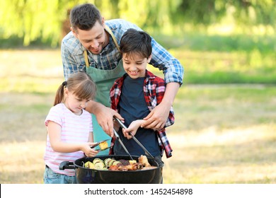 Little children with father cooking tasty food on barbecue grill outdoors - Powered by Shutterstock