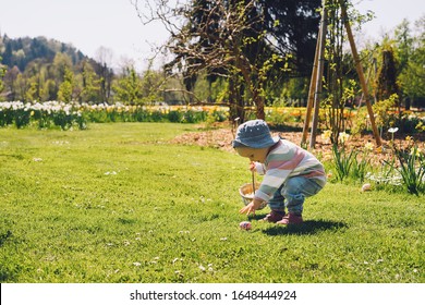 Little children gathering painted decoration eggs in spring park  Kids hunt for egg outdoors  Festive family traditional play game Easter  Colorful Easter eggs in basket 