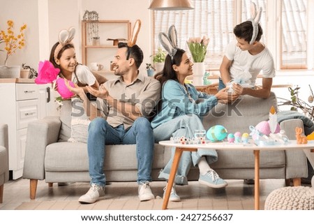 Little children giving their parents gift eggs at home on Easter Day
