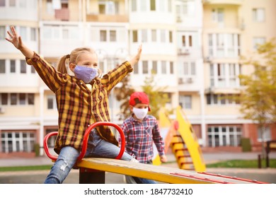 Little Children With Medical Face Masks On Playground During Covid-19 Quarantine