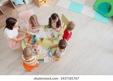 Little children with nursery teacher drawing at table in kindergarten, top view - Powered by Shutterstock