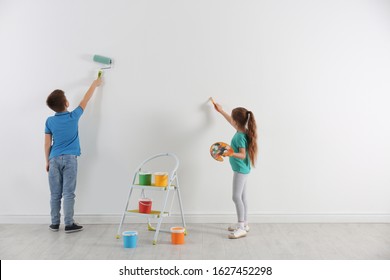 Little Children Painting On Blank White Wall Indoors