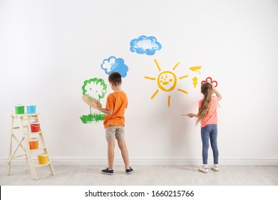 Little Children Painting On White Wall Indoors