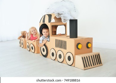 Little children playing with cardboard train in light room