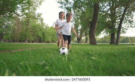 little children are playing football. people parks and nature concept. beautiful boy and girl playing with a soccer ball in nature, running on the grass and laughing lifestyle - Powered by Shutterstock