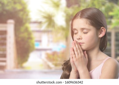 Little children praying with folded palms and close eyes