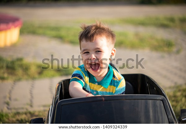 Little children in toy car and  rest in city\
park. Closeup portrait