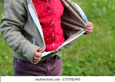 Little Children's Handles Unzip Zip On A Jacket On A Background Of Blurred Green Grass