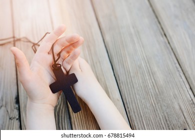 Little Childs Hands Holding Wooden Rosary. Child Praying