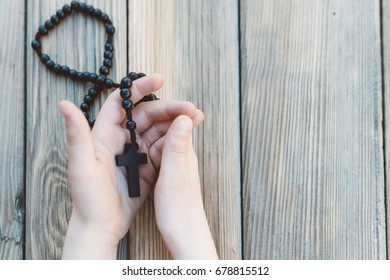 Little Childs Hands Holding Wooden Rosary. Child Praying