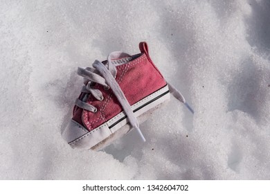 Little Child's Pink Sneaker Shoe Isolated In Winter Snow.