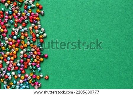 Little christmas colourful jingle bells on green background with copy space for text. Holiday festive happy new year concept. Idea for greeting postcard, poster, banner, web. Mockup, flatlay, top view
