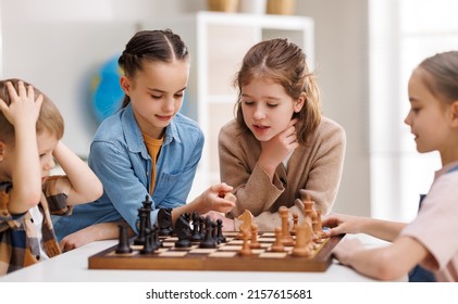 Little classmates gathering around table and pondering over move while learning to play chess during lesson at school - Powered by Shutterstock