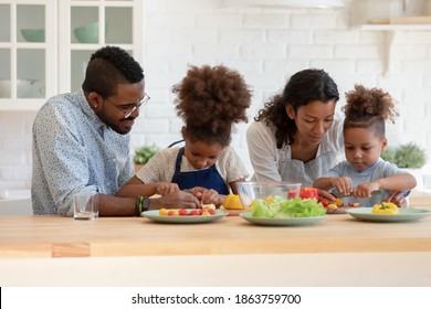 Little cooks. Focused attentive black parents mother and father giving culinary lesson to preteen daughter and small son, two children involved in preparing healthy food by mom and dad at home kitchen - Powered by Shutterstock