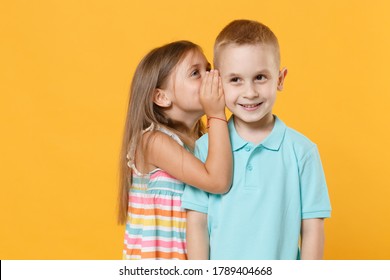 Little Couple Boy Girl 5-6 Years Old In Blue Pink Clothes Shirt Dress Have Fun Isolated On Yellow Background Children Studio Portrait. People Childhood Lifestyle Concept Whispering Secret Behind Hand.