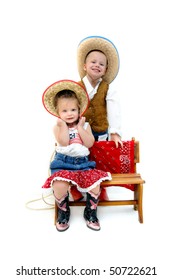 Little Cowboy And Cowgirl Pretend They Are In The Wild West. Cowgirl Pulls Her Hat Against Her Face And The Cowboy Gives A Sheepish Grin As He Attempts To Get A Kiss.