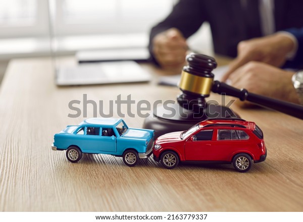 Little crashed autos on table in courtroom.\
Gavel and two small toy car models on desk in courthouse. Concept\
of lawyer services, civil court trial, vehicle accident case study,\
and insurance coverage
