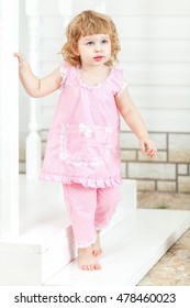 Little Curly Girl In A Pink Dress And Bare Feet Coming Out Of The House And Go Down The Stairs.