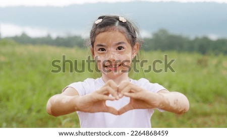 Little cute alpha young albino vitiligo small girl relax smile give heart hand sign look at camera. Melanin face body care hair color of asia people gen z kid self love happy proud of diverse skin.