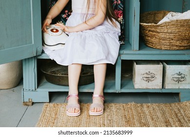 little cute Armenian girl sit in retro vintage wardrobe and playing hide-and-seek in country house and having fun with disk analog phone, concept of simple life and spring
